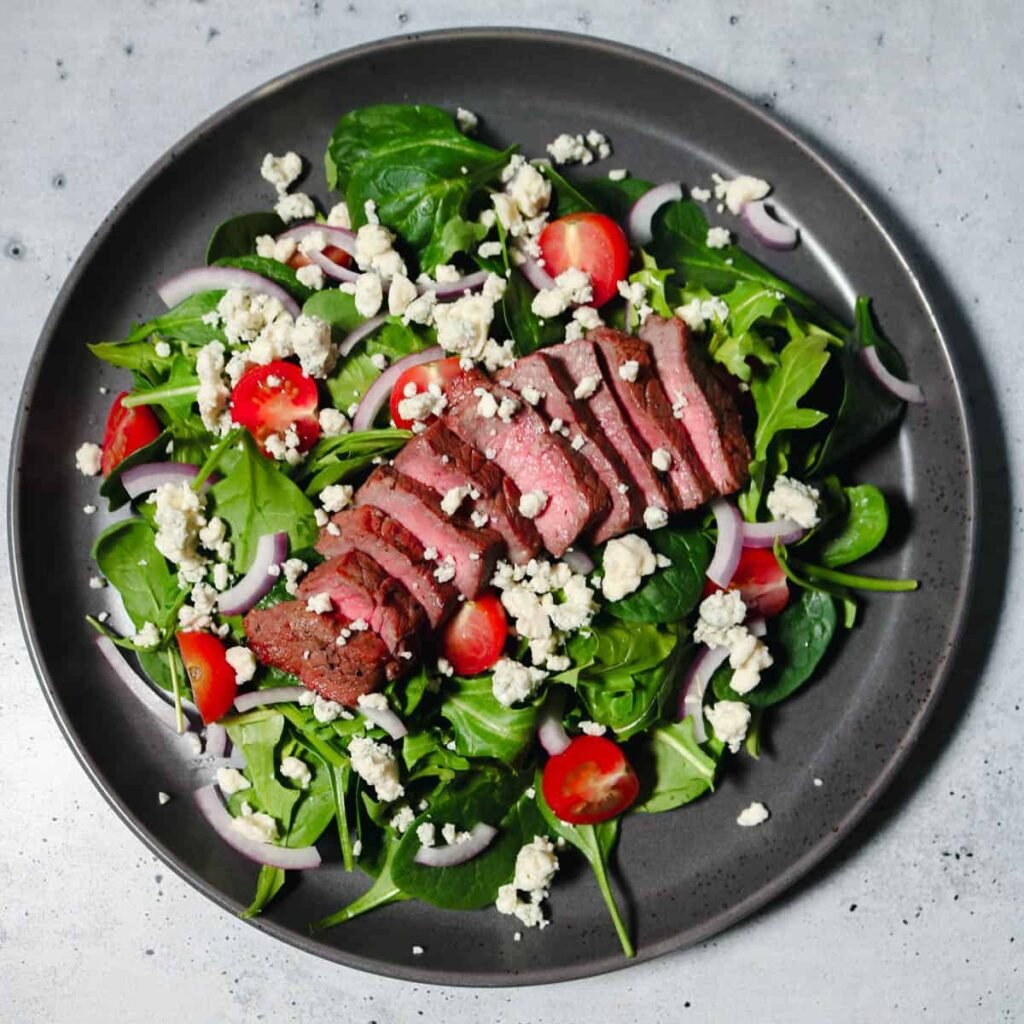 Arugula and spinach steak salad with gorgonzola and balsamic vinaigrette, a flavorful dish for healthy New Year’s dinner or meal prep ideas. 