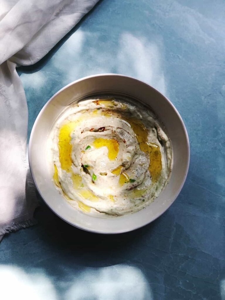 Greek yogurt and avocado dip in a bowl surrounded by veggie sticks and tortilla chips, a creamy and healthy New Year’s snack.