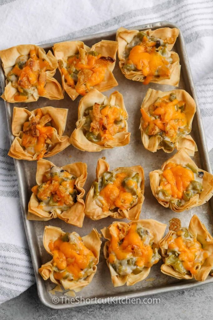 Green bean bites wrapped in flaky pastry, displayed on a serving tray with dipping sauce, a unique New Year’s Eve appetizer.