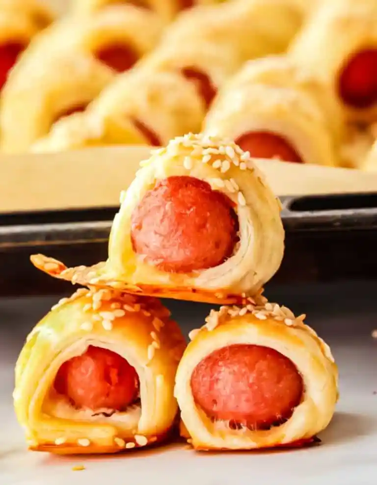 Mini hot dog appetizers wrapped in crescent rolls on a tray, a kid-friendly snack for New Year’s Eve.