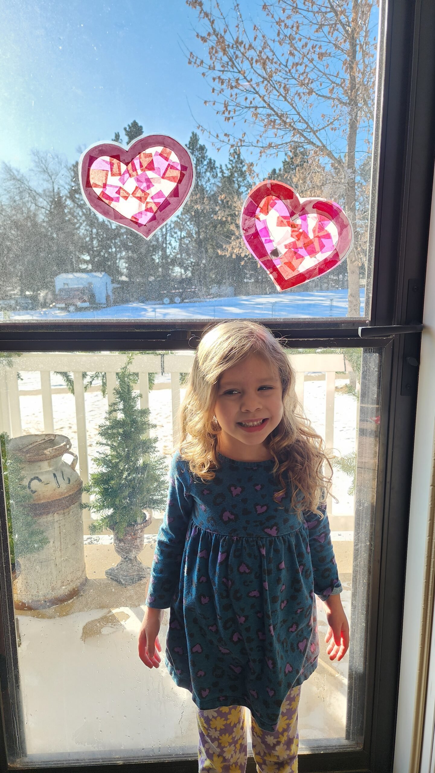 Valentine’s Day craft idea: A heart-shaped sun catcher made with pink and red tissue paper, glowing beautifully on a window