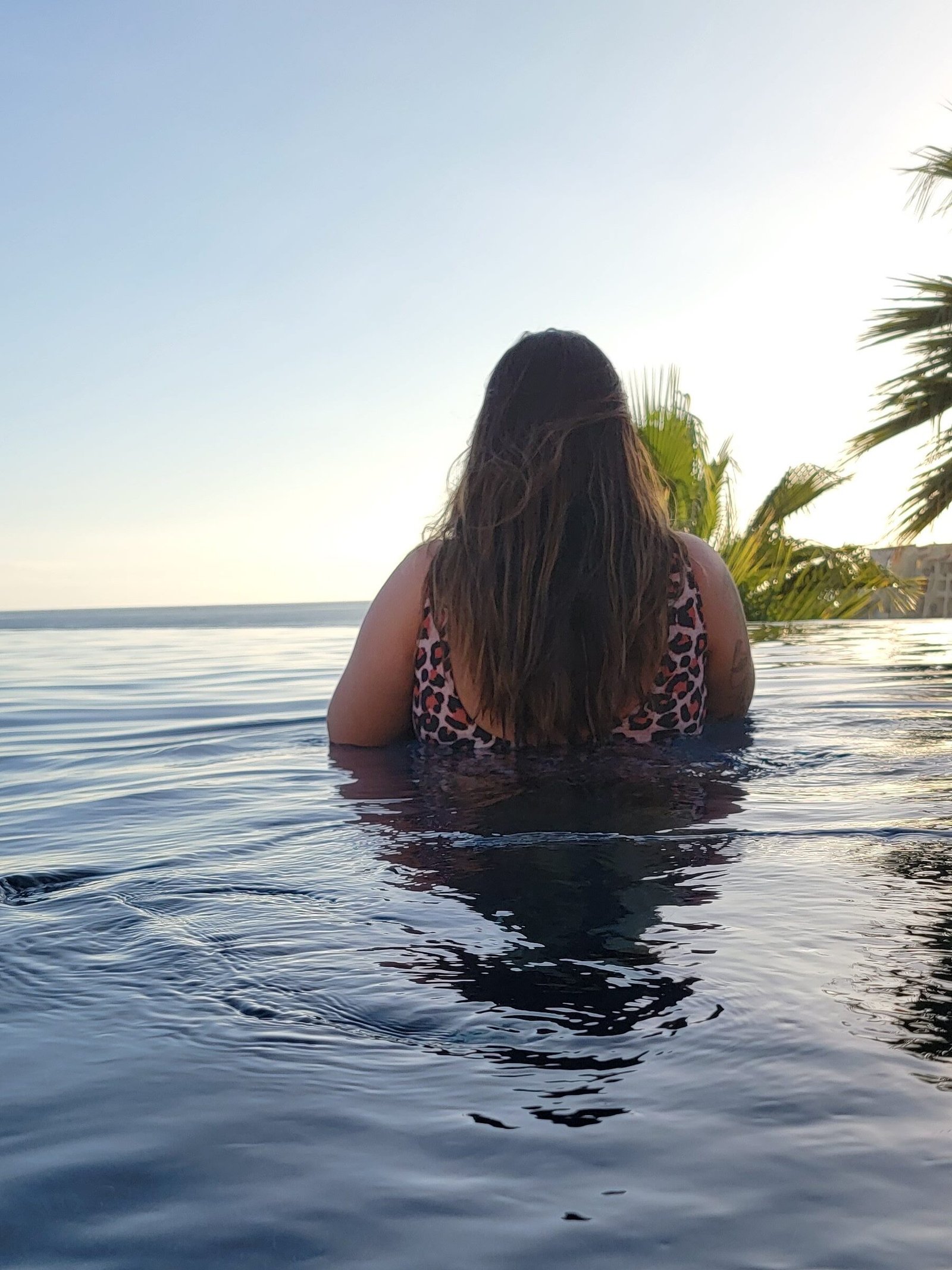 Behind me in an infinity pool in Cabo San Lucas, capturing romantic travel inspiration and carefree connection.