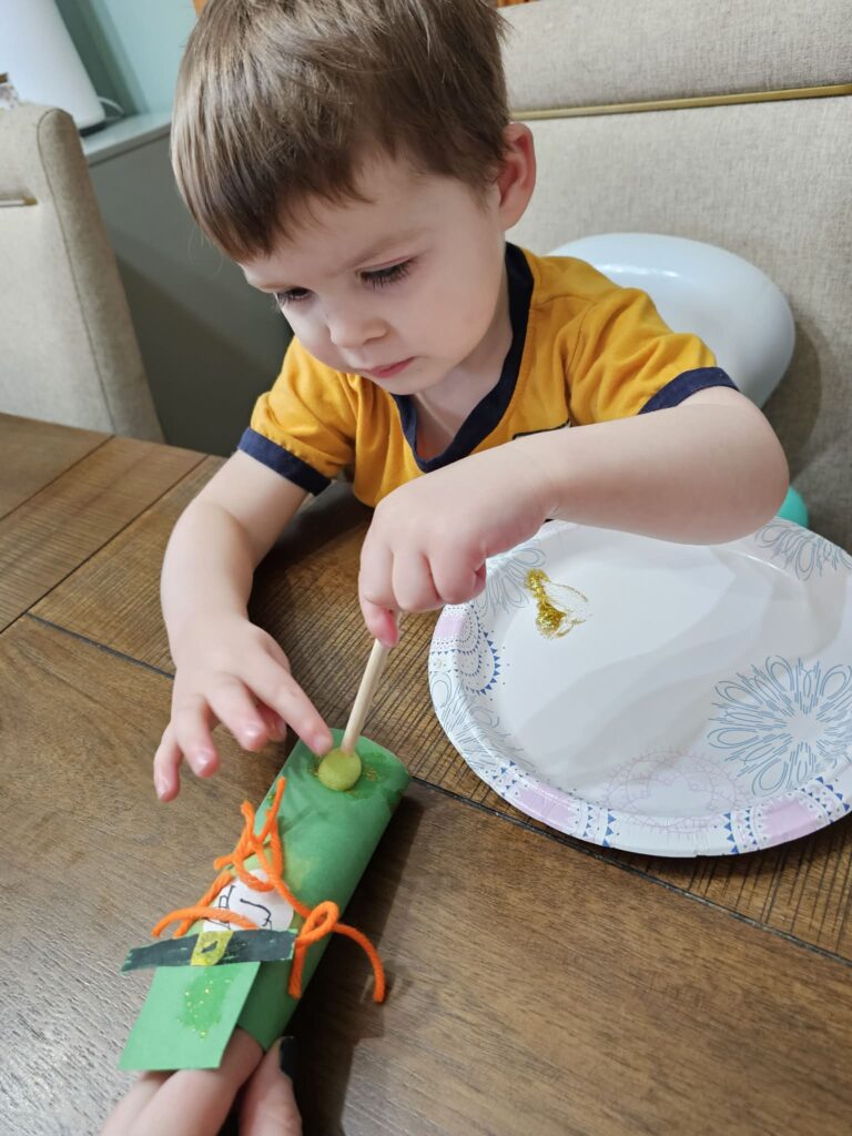 Toddler Paper Roll Leprechaun Craft Decorating the Leprechaun in Gold Glitter